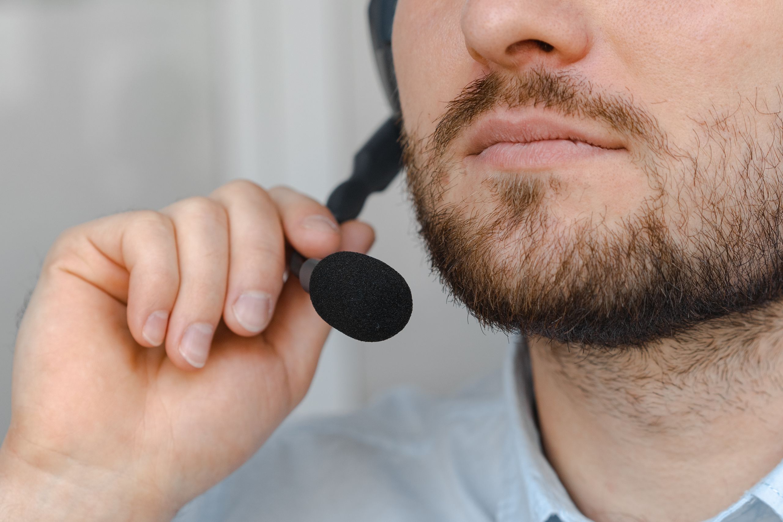 Close-up of a man with a beard holding a microphone headset.