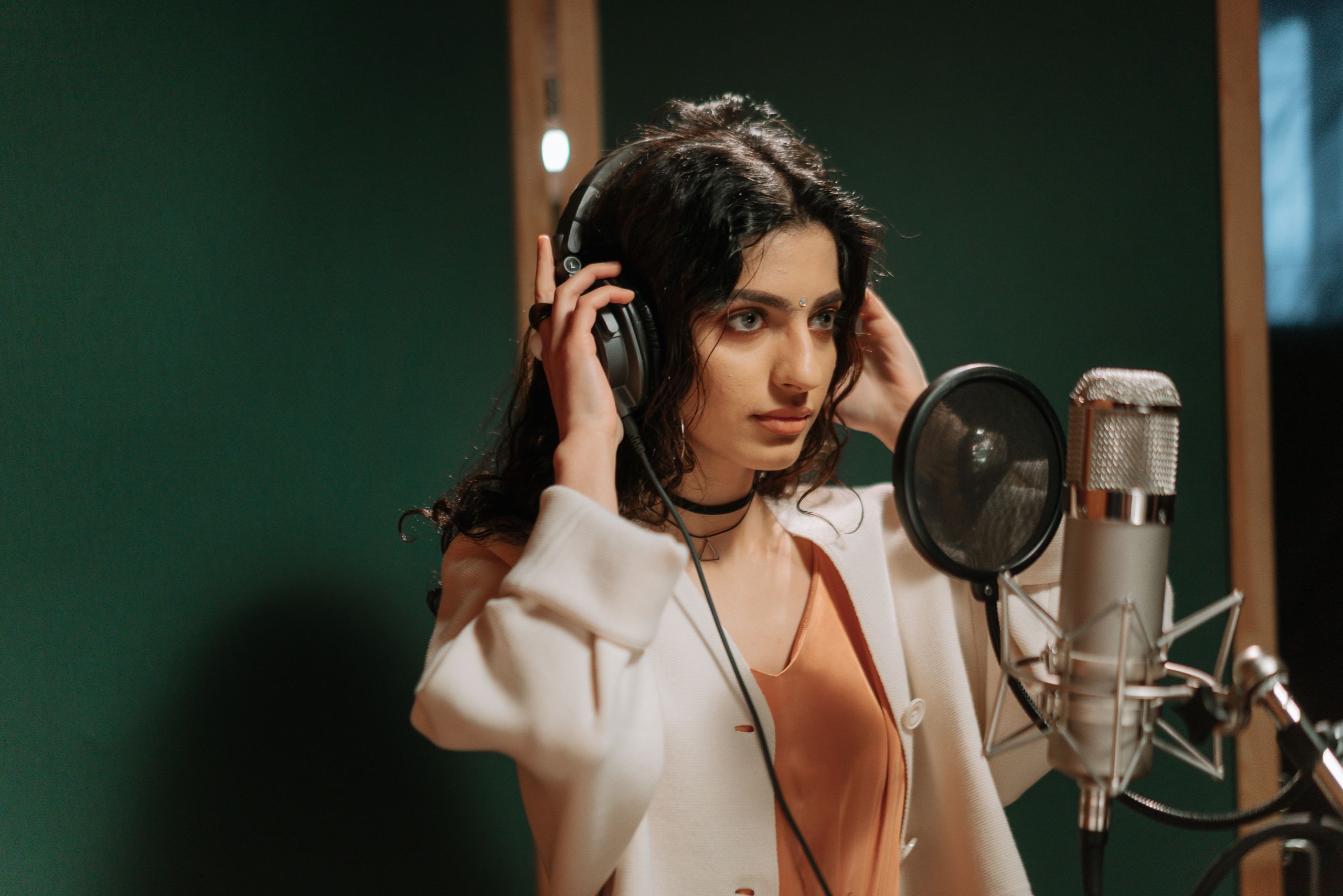 A singer in headphones at a studio microphone