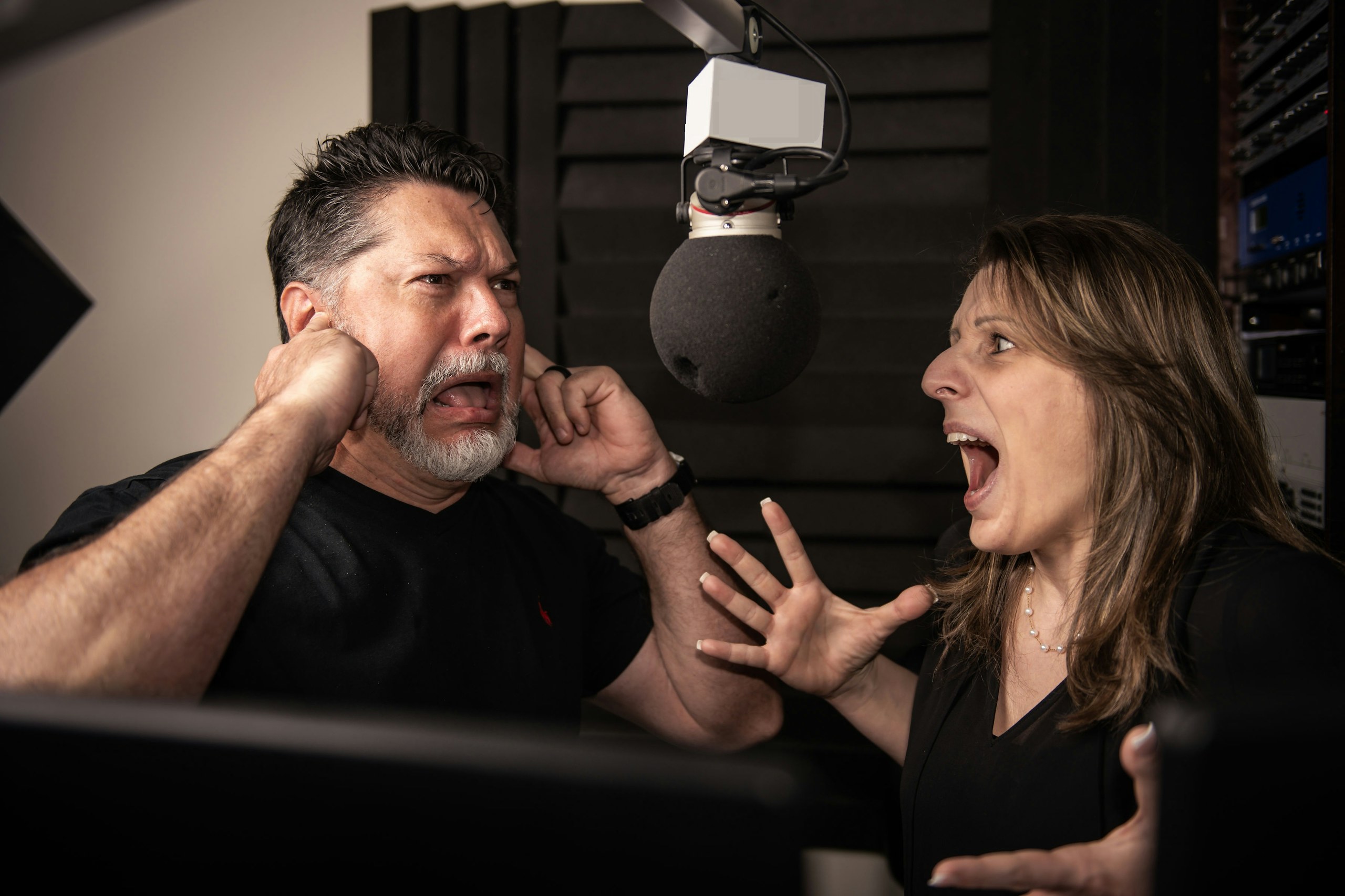 Man covering ears while woman shouts in studio